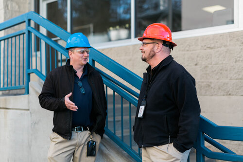 Photo of two men wearing hard hats talking