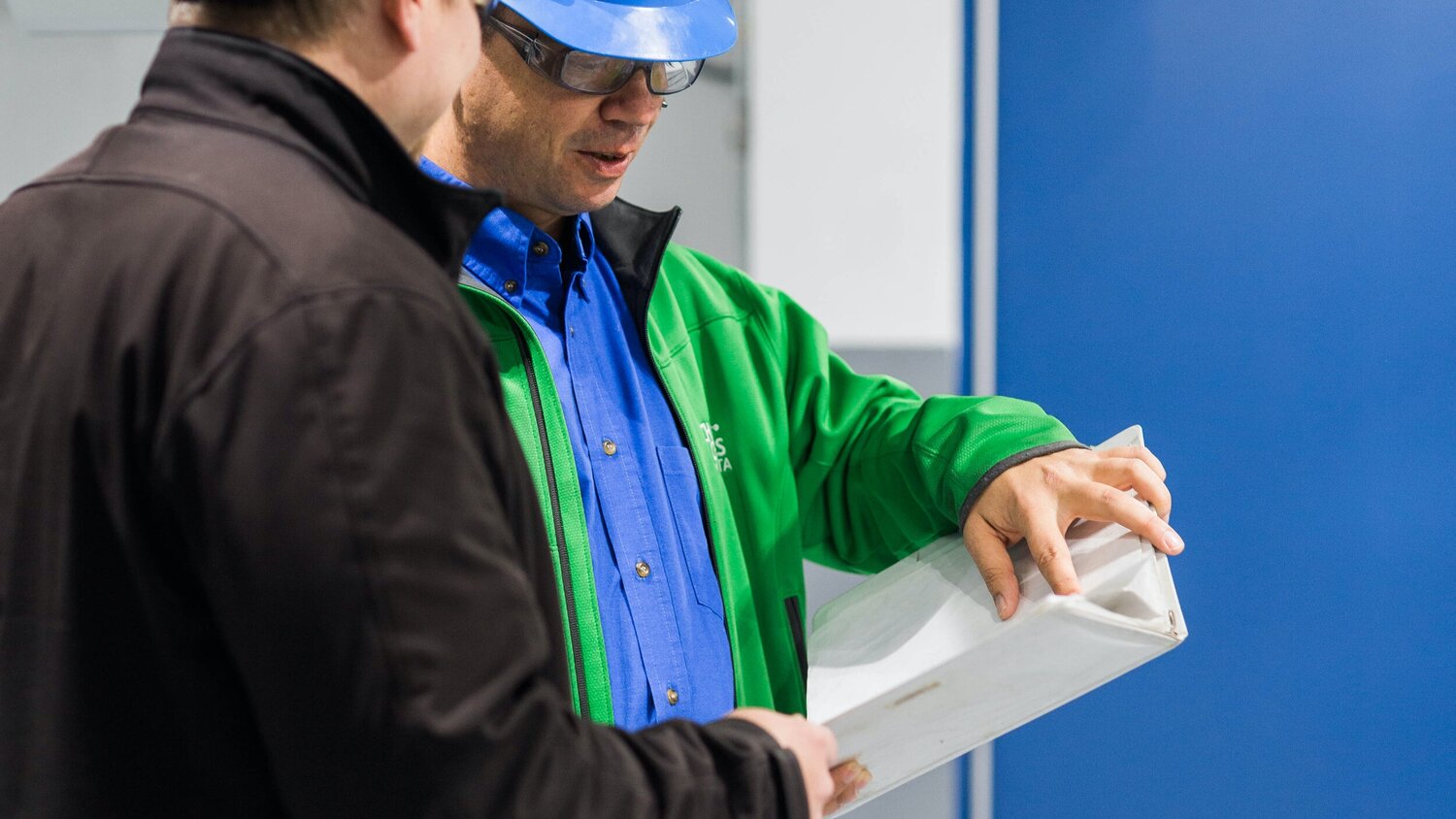 Image of two men talking and looking at binder